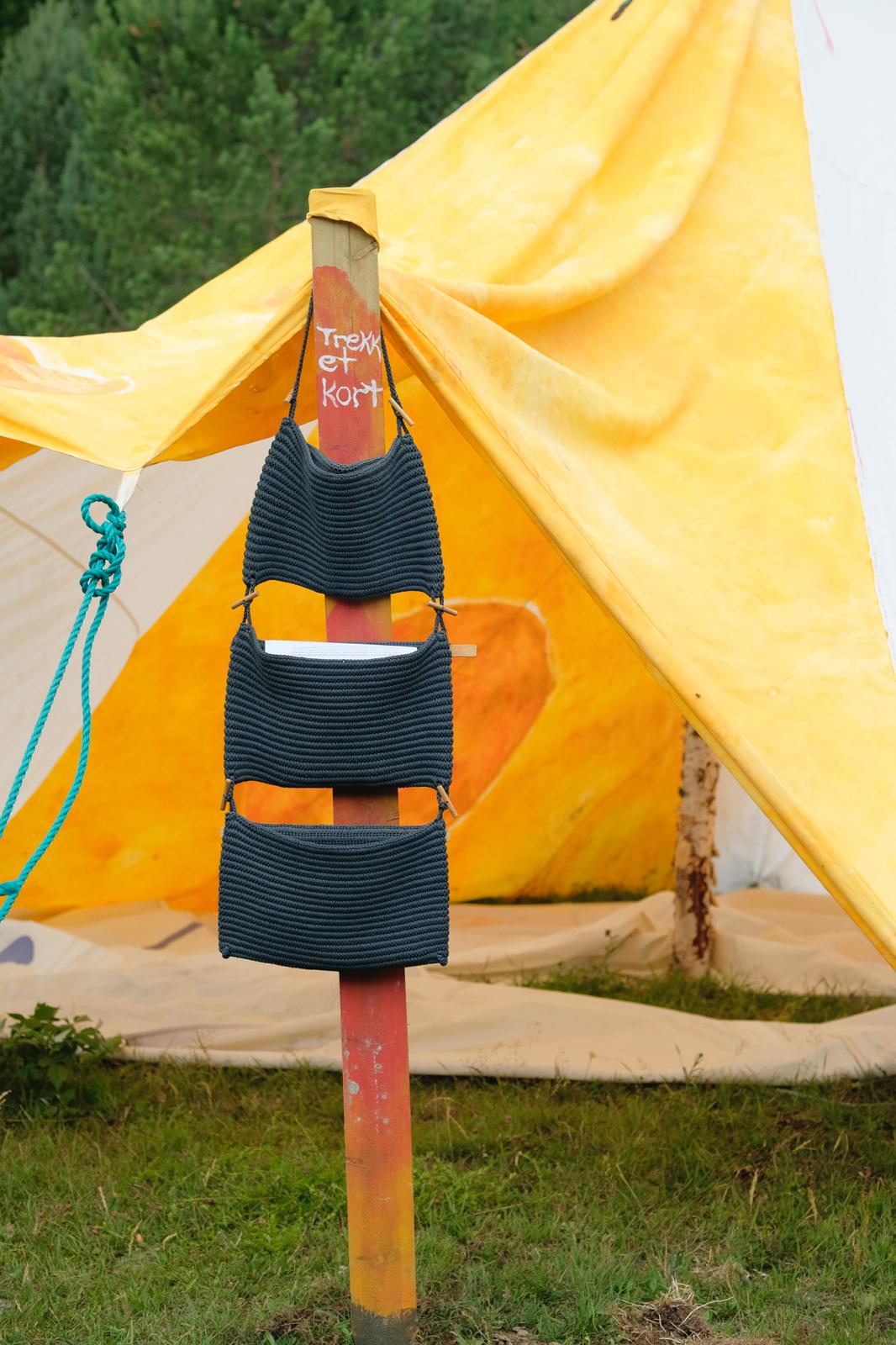 Trekk et kort holder med mantra-kort i strikkede lommer hengende foran det oransje teltet